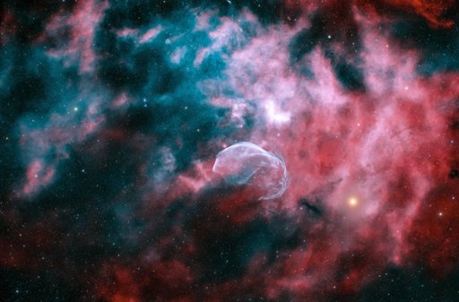 WR 128 — a faint blue ring of ionized gas blown by a Wolf-Rayet star, set in a red nebula field